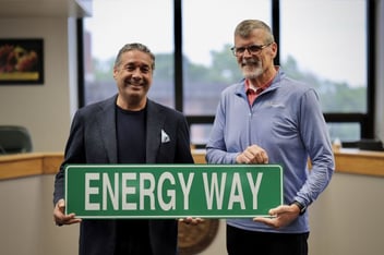 Panasonic Energy President Allan Swan and De Soto, Kansas, Mayor Rick Walker pose holding a street sign that reads "Energy Way"